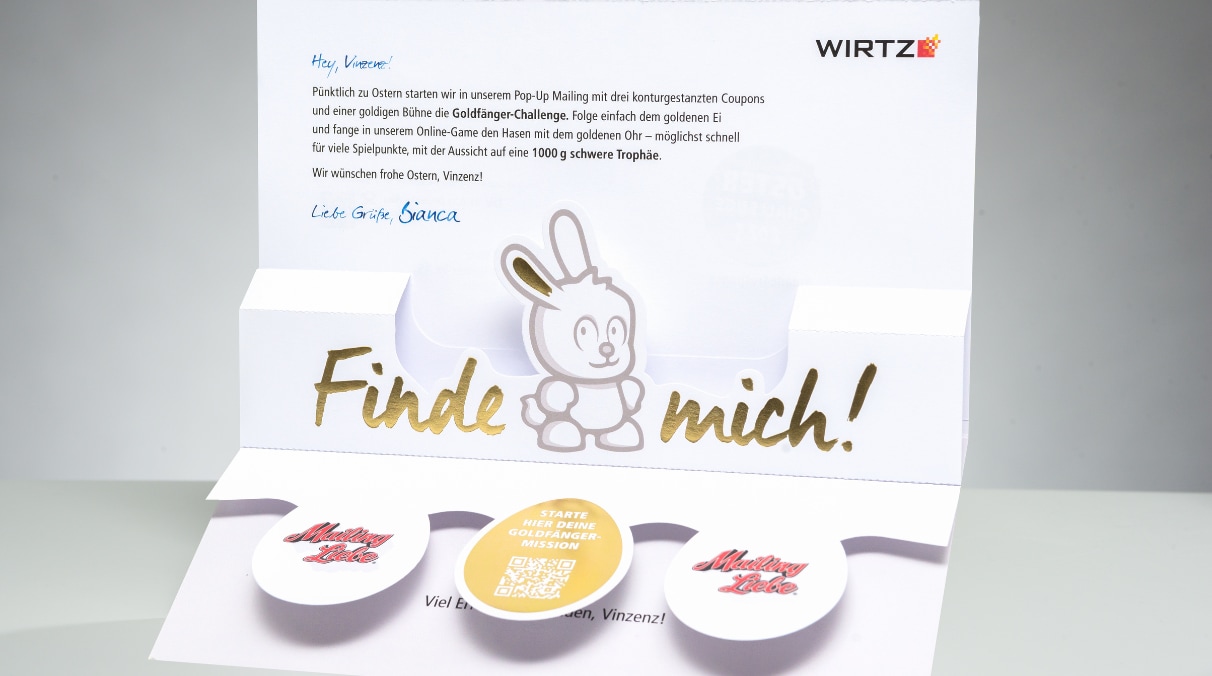 In einer Werbesendung, wird durch eine Pop-up ein Hase mit einem goldenen Ohr hervorgehoben, mit der Aufschrift "Finde mich". Darunter entfalten sich drei Ostereier. Die beiden äußeren tragen die Aufschrift "MailingLiebe". Das igoldene Ei in der Mitte  trägt neben einem QR-Code die Aufschrift "Starte hier deine Goldfänger-Mission".
