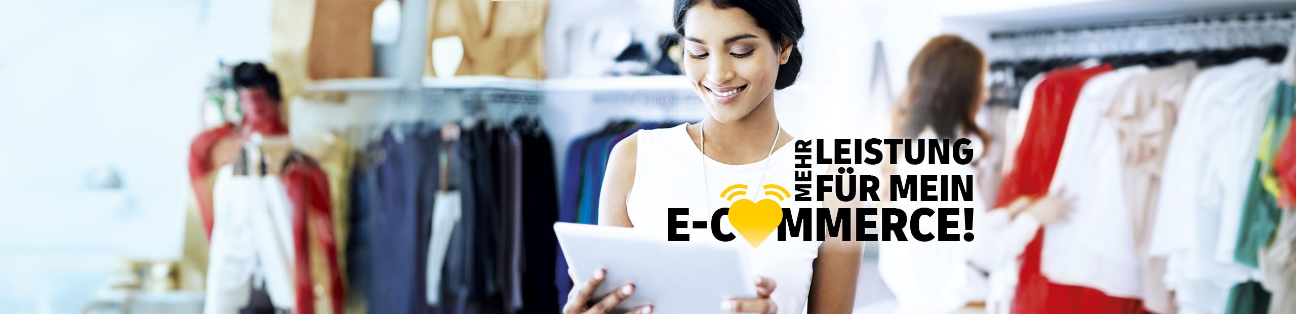 Eine lächelnde Frau steht in einem Laden mit Jeans und schaut auf ein Tablet. Der Schriftzug sagt: Mehr Leistung für mein E-Commerce.