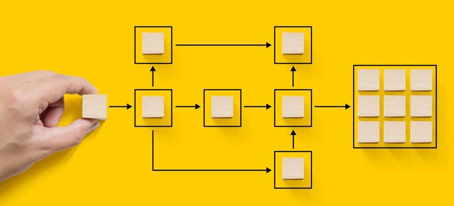 Hand, die einen hölzernen Würfelblock hält und Diagramm auf gelbem Hintergrund arrangiert