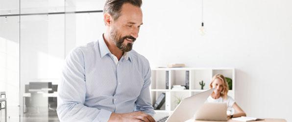 Einfach Posteingang und Akten digitalisieren Mann mittleren Alters sitzt zufrieden mit Laptop in der Hand im Büro