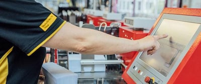 Mitarbeiterin des Deutsche-Post-Lettershops an technischem Gerät, welches für die Produktion bereitsteht