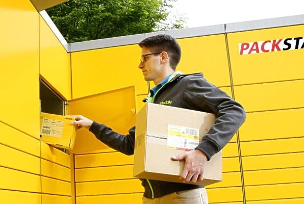 Mann mit Paket an Packstation