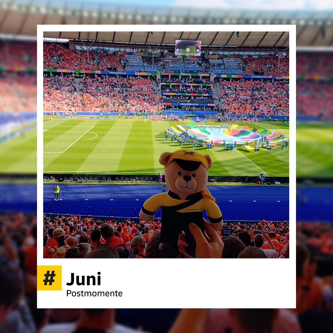 Blick in ein voll besetztes Fußballstadion. Im Vordergrund hält jemand ein Plüsch-Maskottchen der Deutschen Post mit Uniform hoch. Hashtag: „#Juni – Postmomente“.