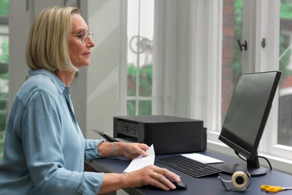 Frau am PC druckt Internetmarke