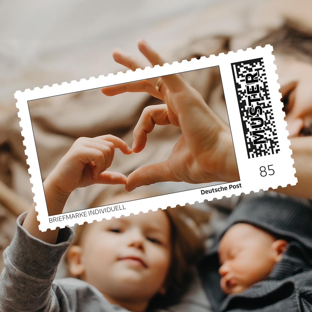 Individuelle Briefmarke mit einem emotionalen Familienmotiv: Zwei Kinder formen mit ihren Händen ein Herz, im Hintergrund ein gemütliches Zuhause.